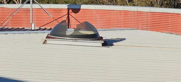 Broken dome-shaped skylight on a rooftop, with visible cracks and damage.