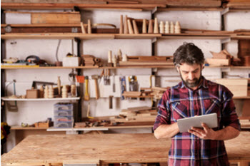 A man in a wood working workshop looking at a tablet