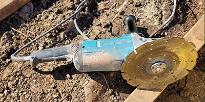 A blue nine inch angle grinder on a dirt ground