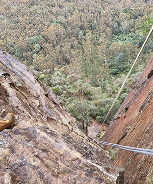 Looking down a cliff face with an abseiling rope