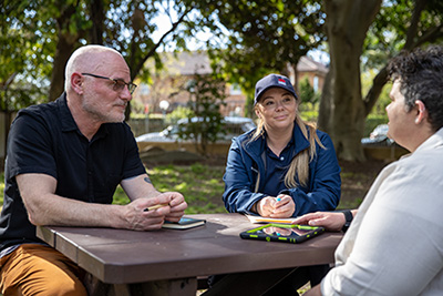 SafeWork NSW Inspector talking to two people.