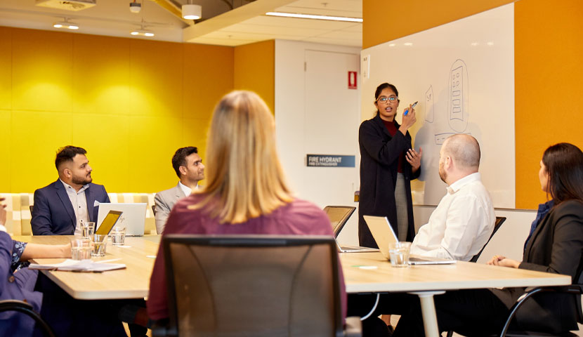 A worker presenting to a group in a corporate office.