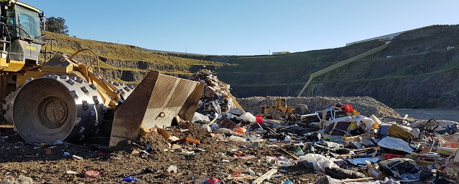 A heavy industrial landfill compactor in the open pit of the waste management facility in Eastern Creek.