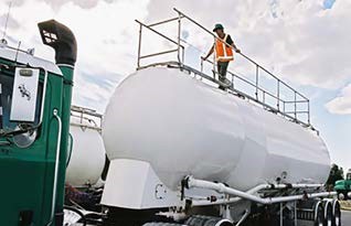 Photo of a worker using a pneumatic guard railing on a tanker