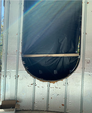 Window hole of a building under construction, covered with a tarpaulin