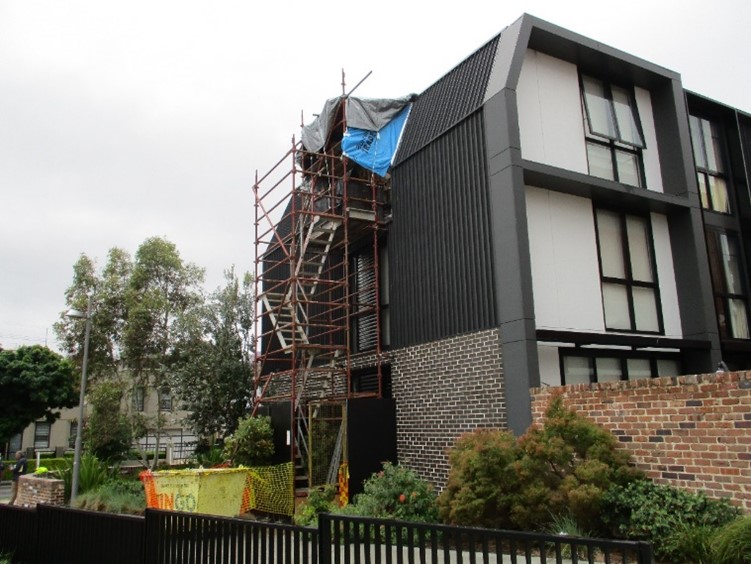 Image of a brown townhouse with scaffolding on one side