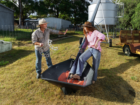 Two workers in a field, standing near a harvester. They are facing each other having a conversation.