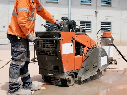 Worker in orange vest operating large machine