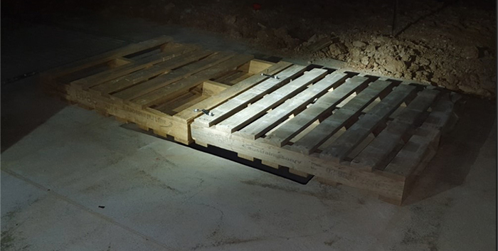 A construction site with a void, covered by two wooden pallets.
