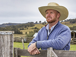 Farmer next to fence on farm