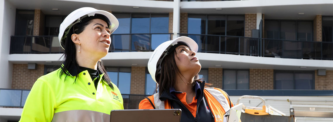 Two workers on a construction site, wearing PPE. 