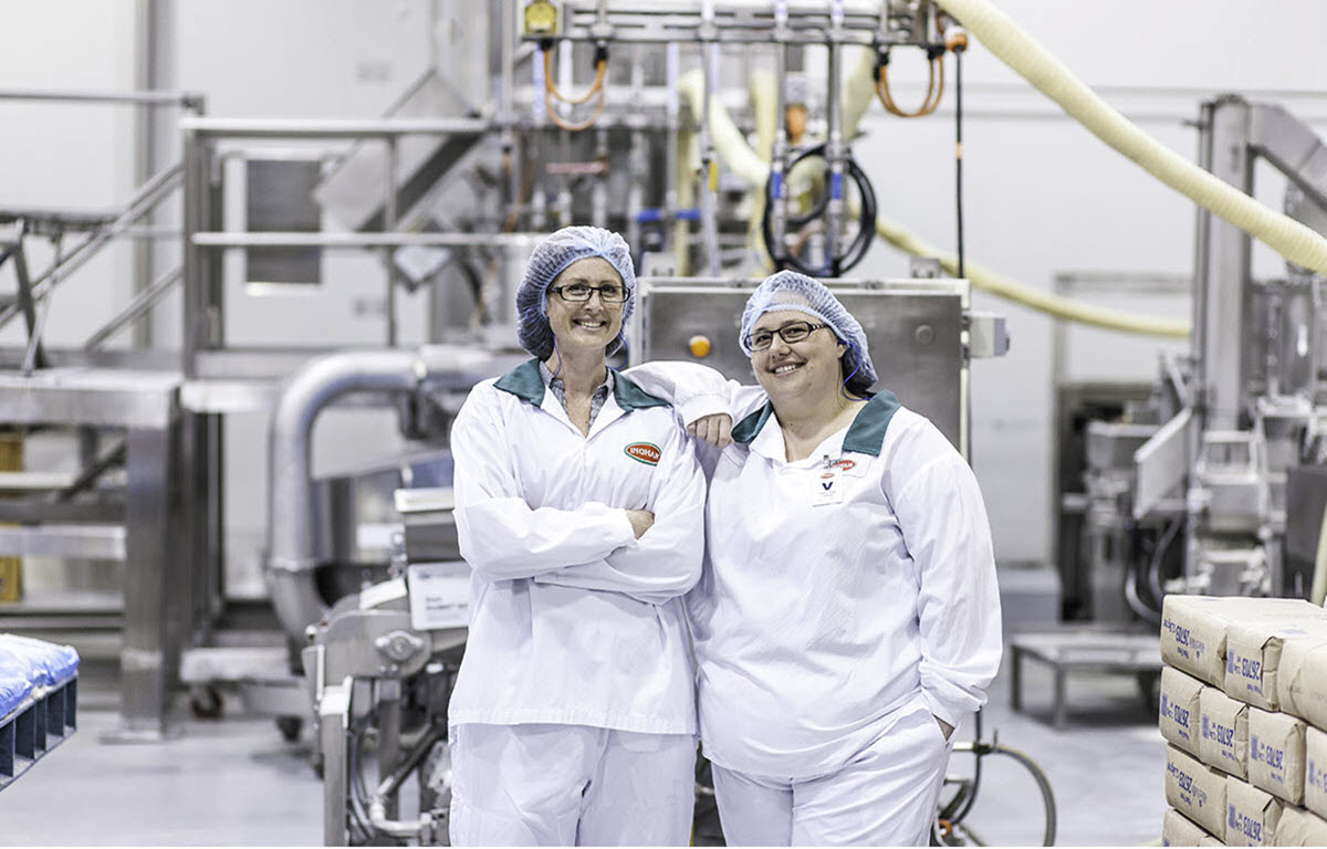 Two ladies standing together in a food factory