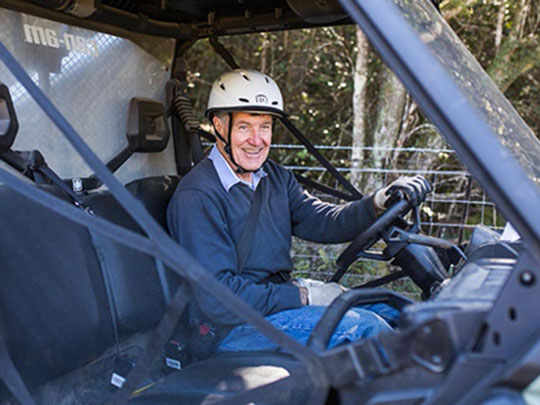 A man sitting in a side-by-side vehicle wearing a seat belt and a helmet