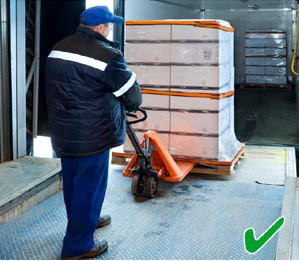 Photo of a worker using a pallet jack and tailgate lifter to load stock into a truck