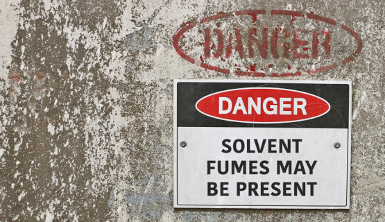 Sign on a concrete tank stating Danger: Solvent fumes may be present