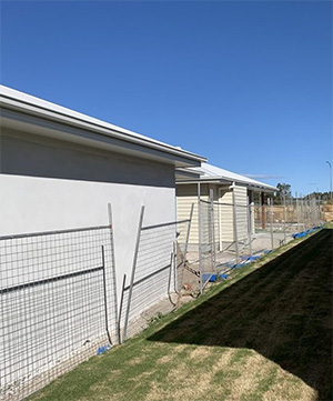 Side of the residential dwelling under construction with a fence