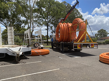 A car park with a truck loading with roles of orange electrical conduit
