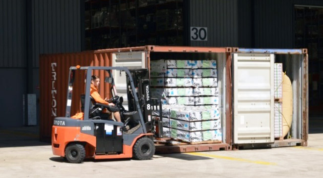 Image of driver unloading container with forklift - on even ground 