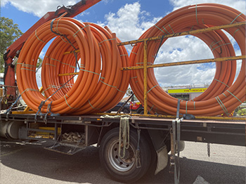 Large orange rolls of electrical conduit on the back of a truck