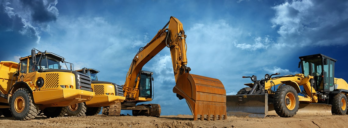 Five large bright yellow earthmoving construction vehicles lined up in a row. The background shows a blue sky with scattered clouds.