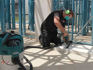 A worker wearing PPE, cutting engineered stone on a work site.