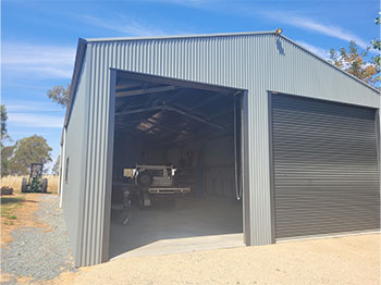 An external view of a large shed with two doors, one with a closed roller door.