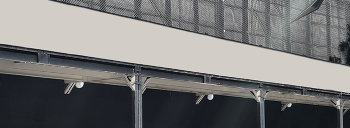 Overhead protective mesh and temporary barrier walls set up at a construction site.